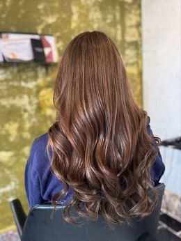 Zij-/achteraanzicht van lang blond balayage haar met face-framing en losse waves, gestyled door Anthe van Salon Couleur.