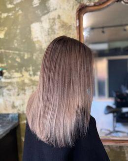 Achteraanzicht van halflang, zacht golvend blond haar met koele highlights, geknipt en gestyled door Anthe van Salon Couleur.